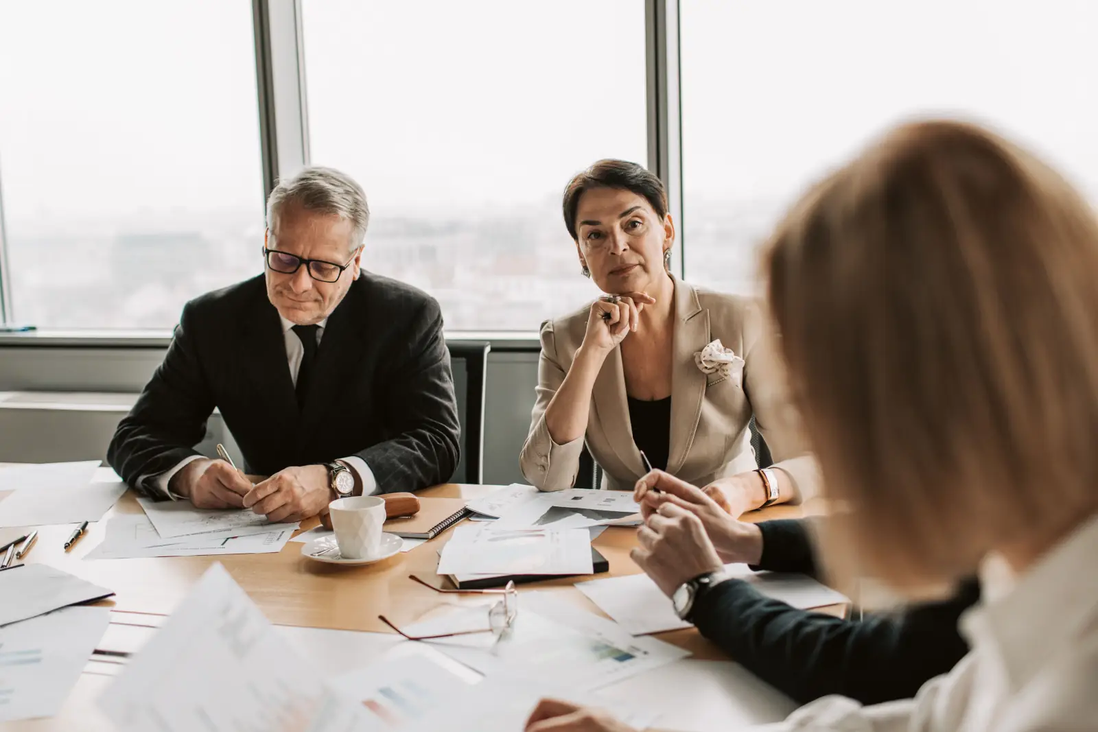 Colleagues from different roles discussing reports around a meeting table