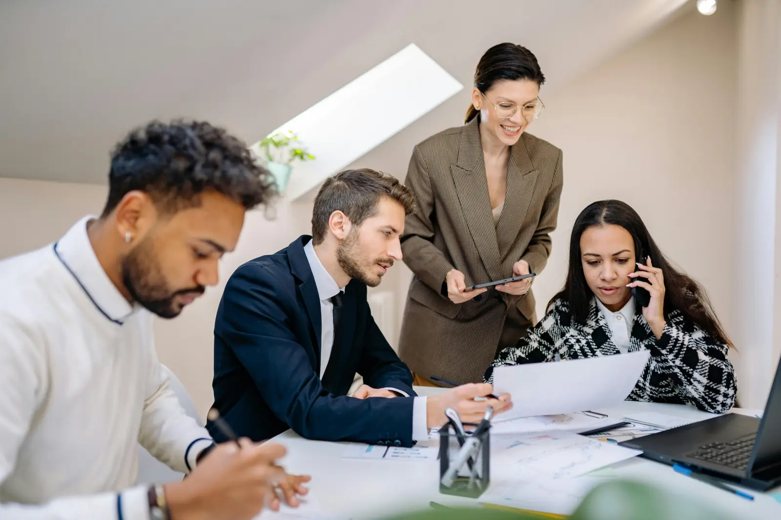 Four colleagues working through reports and charts together at a meeting table